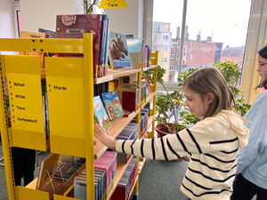 Kinder gehen in der Bücherei umher