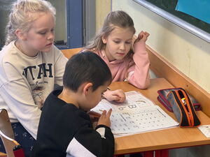Drei Kinder vor einem Arbeitsheft
