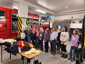 Schulkinder in der Halle neben dem Feuerwehrfahrzeug