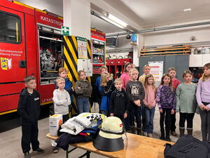 Schulkinder in der Halle neben dem Feuerwehrfahrzeug