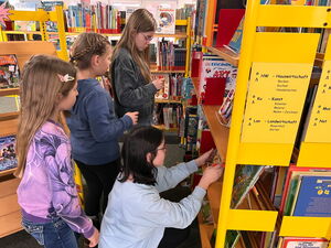 Kinder gehen in der Bücherei umher