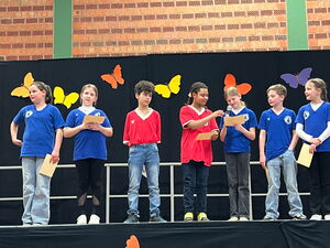 7 Kinder auf dem Podium tragen etwas vor