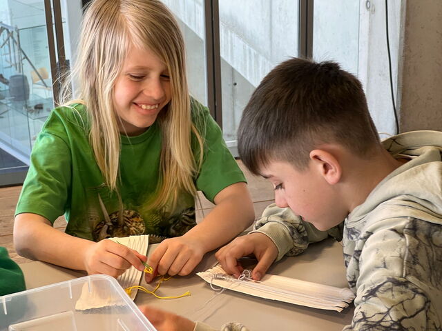 Schülerinnen und Schüler beim Weben