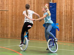 Kinder beim Einradfahren in der Turnhalle